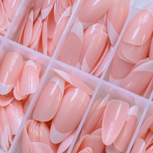 Macro shot of pink French almond press-on nails organized in a clear compartment box