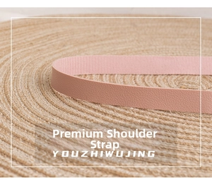 Detail eines rosa Leder-Schultergurts mit natürlicher Narbung auf gewebtem Strohhintergrund