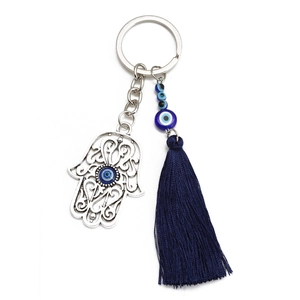 Detail of silver Hamsa Hand and Evil Eye charm with elegant dark blue tassel
