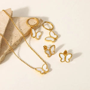 Detail view of 18K gold butterfly necklace and earrings set with white shell inlays