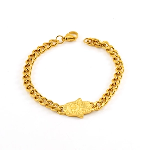 Detail of gold Cuban chain bracelet featuring a Hamsa hand pendant on a white background