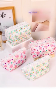 Detail of floral quilted makeup bags with white lace trim and heart-shaped zipper pulls