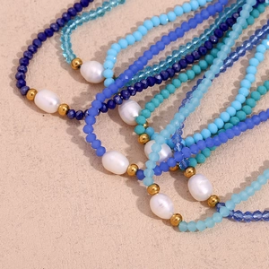 Macro view of blue crystal beads with white baroque pearls and golden metal spacers