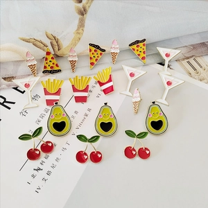 Flat lay of colorful enamel food pins including pizza, ice cream, and fries on textured fabric