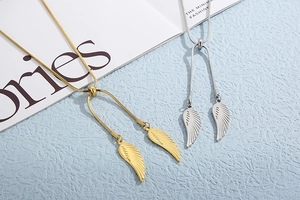 Detail of gold and silver angel wing pendants on sleek snake chains over a book