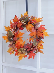 Close-up of fall wreath featuring vibrant orange maple leaves and red berry clusters