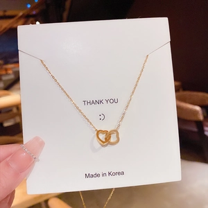 Close-up of gold double heart pendant necklace with fine chain on a display card