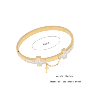 Detail view of a gold stainless steel cuff bracelet with sparkling crystal cross accents