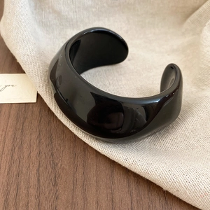 Macro detail of glossy black acrylic resin cuff bracelet with polished mirror surface