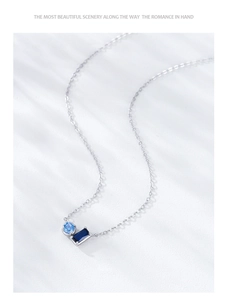 Detail of silver necklace featuring round light blue and rectangular dark blue gemstones