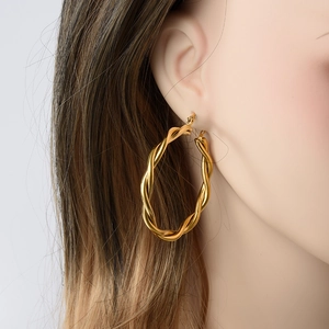 Polished gold-plated stainless steel twisted hoop earrings shown on a model side profile
