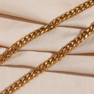 Close-up of golden stainless steel chunky chain necklace on beige silk fabric