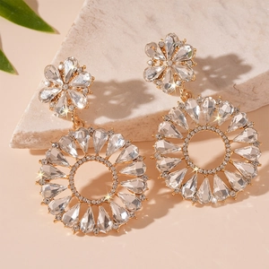 Elegant gold flower hoop earrings with crystal rhinestones on a marble display
