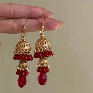 Close-up of vintage Jhumka earrings with gold hollow domes and red teardrop beads