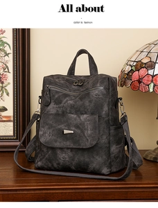 Detail eines grauen Retro-Rucksacks mit gewaschener Lederstruktur und Bronze-Hardware auf Holz