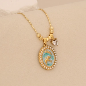 Macro shot of gold stainless steel necklace with enamel bird charm and pearl detail