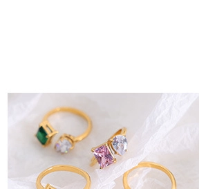 Macro detail of gold open ring featuring rectangle emerald and pink synthetic gemstones