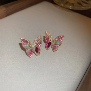 Close-up of colorful butterfly stud earrings with pink crystals and gold-tone inlay