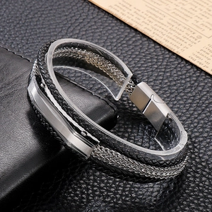Detailed macro view of multi-layer black leather braid and silver chain bracelet with magnetic clasp