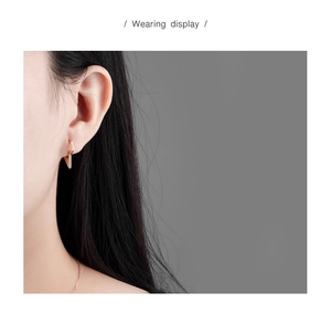 Close-up of minimalist gold geometric lightning bolt hoop earring worn by a model