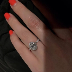 Elegant oval cut zircon halo ring with micro-pave band shown on hand with orange nails