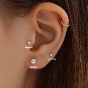 Macro shot of 2mm, 3mm, and 4mm gold round stud earrings with clear sparkling stones