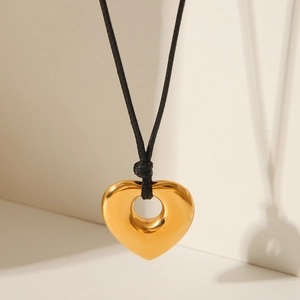 Detailed close-up of a golden heart pendant on a black cord with soft shadows