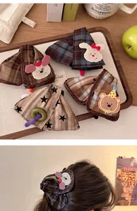 Detailed close-up of cute cartoon plush animal hair scrunchies in various plaid patterns