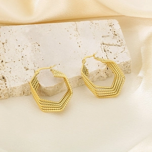 Macro shot of gold geometric hexagonal layered hoop earrings on luxury silk background