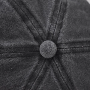 Detail of the stitched crown and top button on a washed dark grey baseball cap
