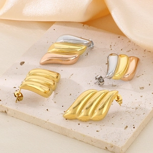 Detailed macro view of 18K gold plated wing earrings in tricolor and gold finishes