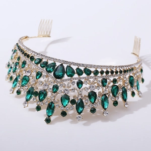 Detailed close-up of golden bridal crown with emerald and clear rhinestones and hair combs