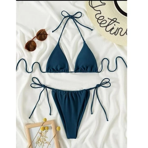 Flat lay of navy blue triangle bikini set with lace-up ties and beach accessories