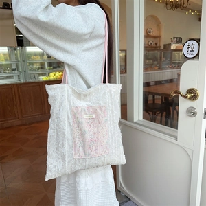 Detailed side view of white lace tote bag with pink vintage pocket on a female shoulder