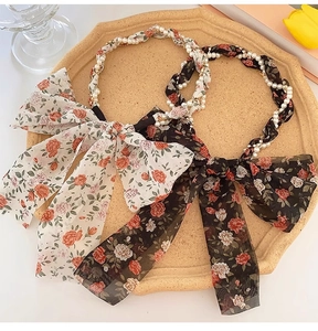 Detail of floral chiffon bow headbands with faux pearl beads in white and black