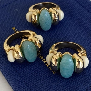 Trio of vintage gold rings with green and beige gemstones on deep blue fabric