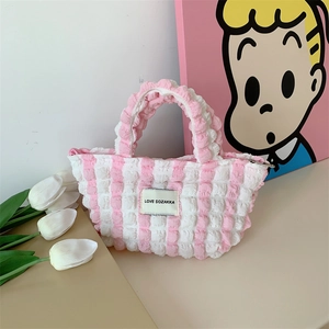 Detail of pink and white striped bubble fabric handbag with zipper and brand label