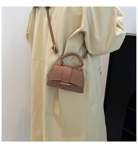 Détail du mini sac marron à texture tissée avec bandoulière réglable sur un trench-coat