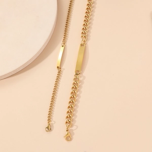 Detailed macro view of gold-plated curb chain bracelets with engravable metal plaques