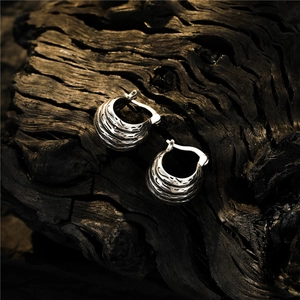 Vintage silver earrings with lava texture and irregular multi-layer design on dark wood