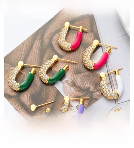 Macro detail of U-shaped enamel earrings with micro-set zircons on fashion magazine background