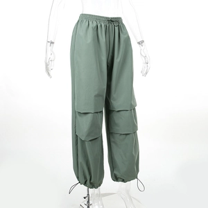 Dettaglio dei pantaloni cargo verde pisello con ampie tasche laterali e coulisse ai polsi