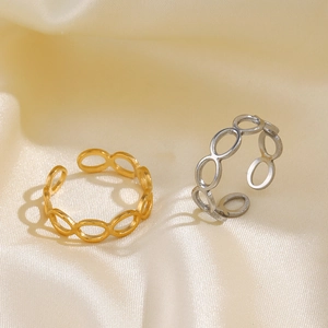 Minimalist gold and silver hollow oval link rings set on beige silk background