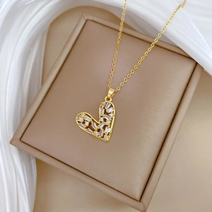Detail of hollow heart pendant with white crystals on a gold chain in luxury packaging