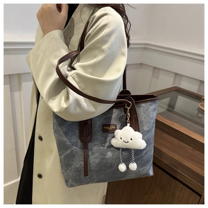Detail of grey marble texture tote bag with brown leather straps and cloud plush charm