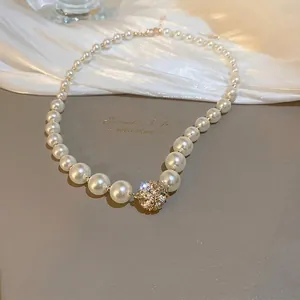 Französische Vintage-Perlenkette mit einer goldenen Kristallkugel auf weißem Seidenstoff