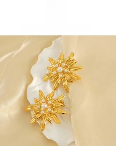 Macro détaillée de boucles d'oreilles fleur plaquées or 18 carats avec perles sur soie élégante