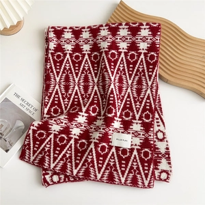 Detail of red and white geometric knit scarf with tribal diamond patterns and brand label