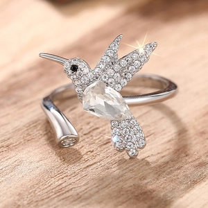 Detail van een kolibrie ring met kristallen vleugels op houten achtergrond