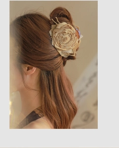Detailed view of large fabric dried rose hair claw clip in khaki on model's hair